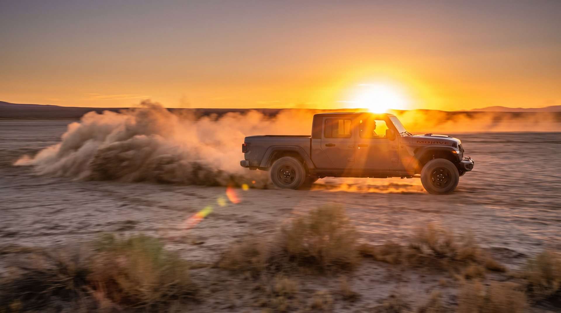 Pickup kicking up dust against a desert sunset
